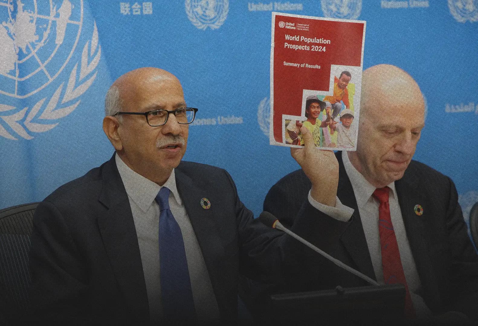 At United Nations Headquarters, a speaker holds up the World Population Prospects 2024 Summary of Results, its cover showing the same children.